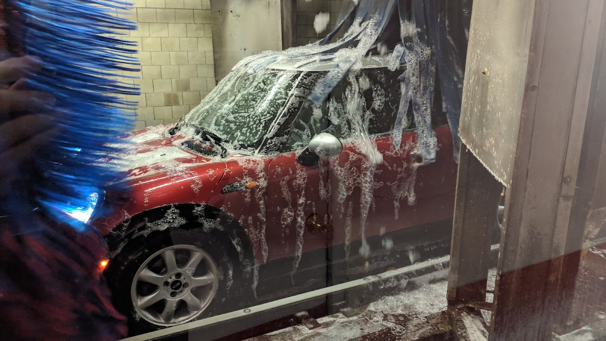 Vehicle being washed with rotating brushes and foam