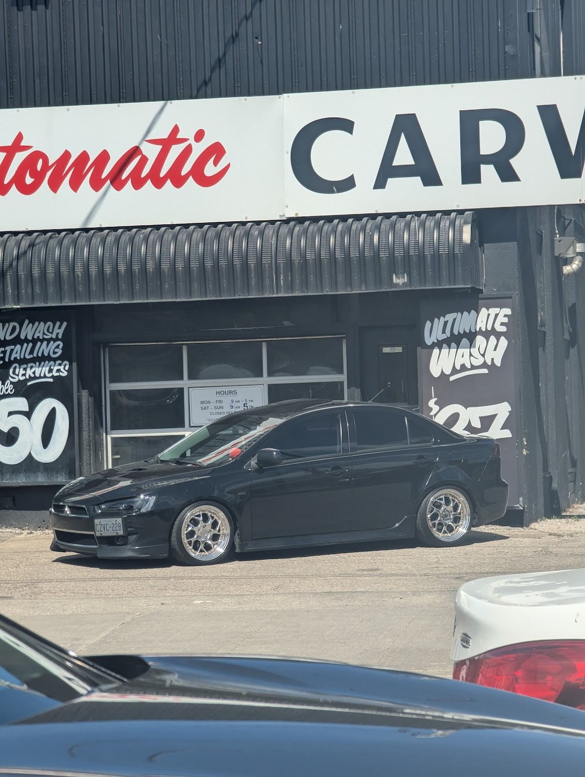 Close-up of storefront signage showing services offered including hand wash and detailing