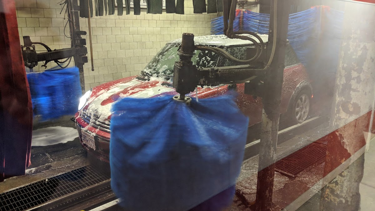 Car going through the wash tunnel with blue cloth strips and water spraying