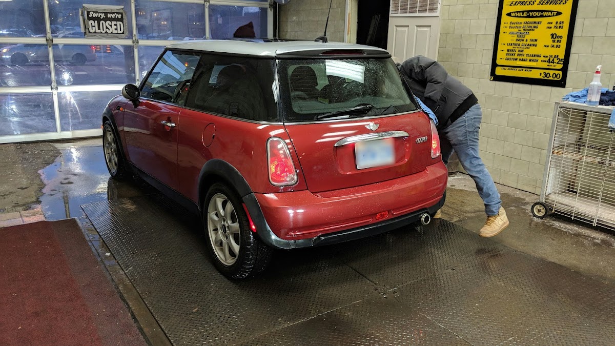Black Honda CR-V gleaming after a wash, positioned in the drying bay of the facility