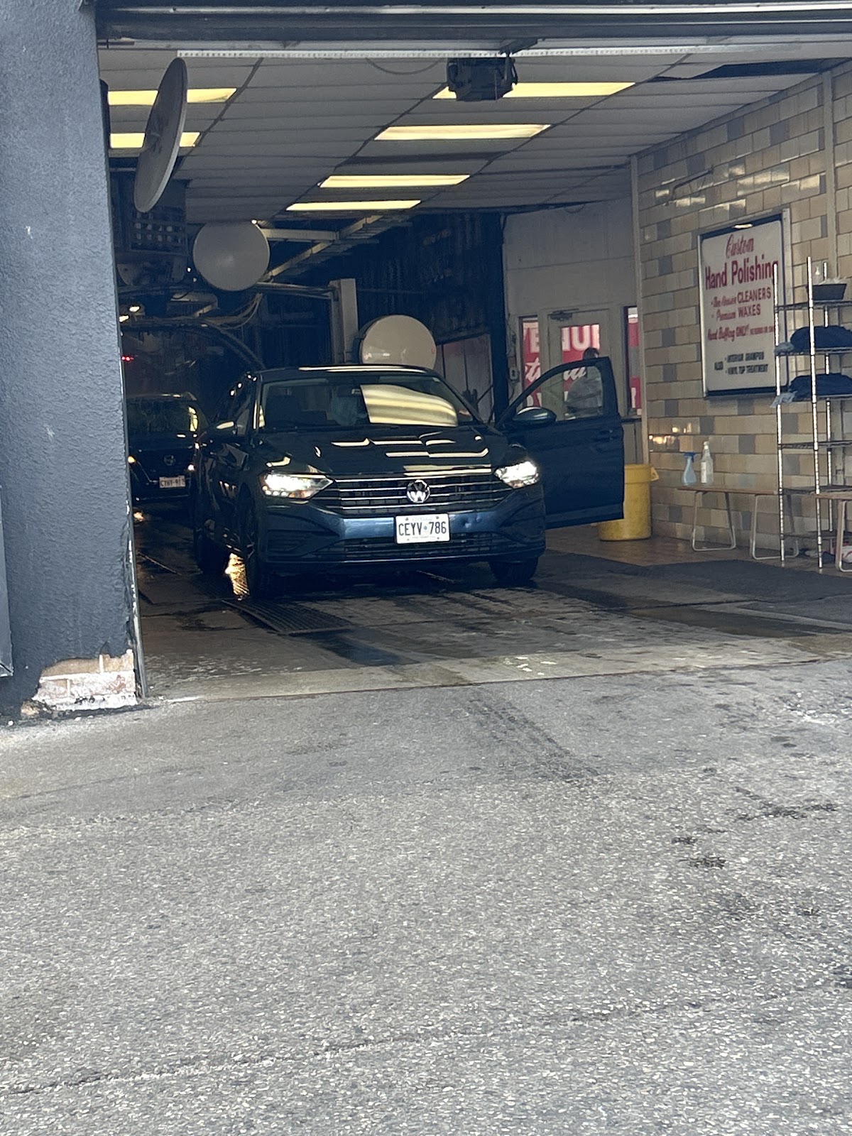 Dark green Volkswagen Jetta exiting the wash bay, gleaming after service