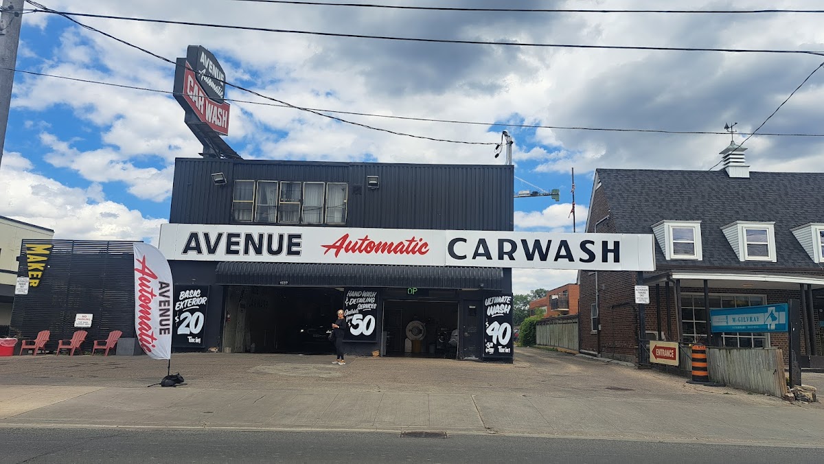 Wide view of the car wash building showing the full Avenue Automatic Carwash banner and feather flag